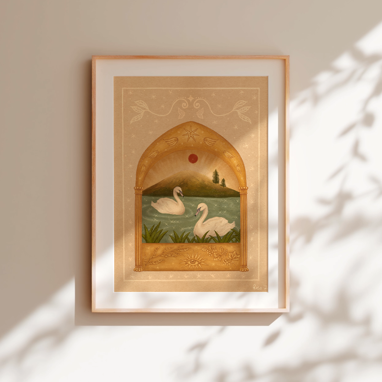 Framed fine art print of two white swans on a teal sparkly lake under a red moon and a golden arch. Angel wings and stars above and grape vines and an eye below. Frame against a white wall